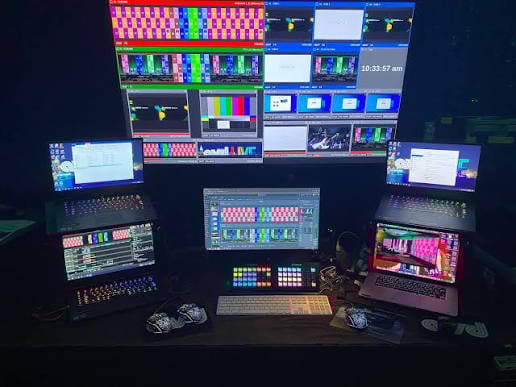 Professional video production workstation with multiple monitors displaying colorful graphics software interface and editing panels