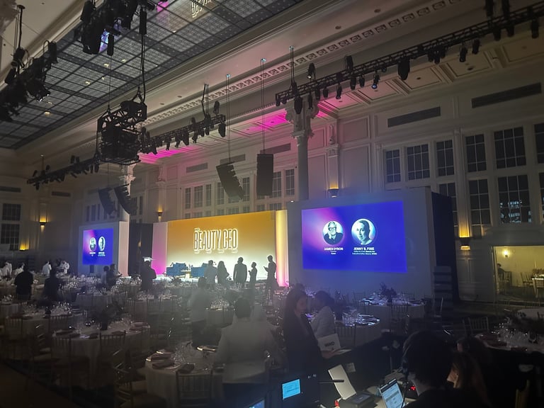 Large event venue with stage displays, colorful lighting and seated attendees during a gala